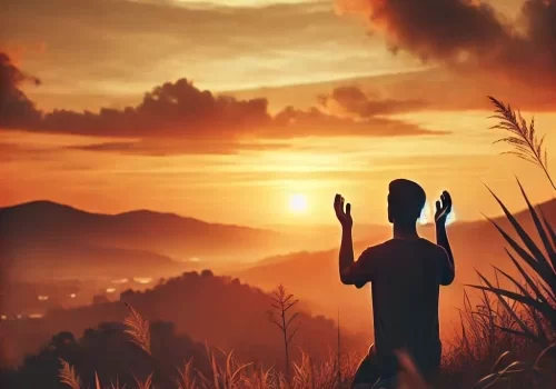 Pessoa realizando uma Oração Poderosa ao pôr do sol com mãos erguidas em um campo aberto, representando conexão com Deus e paz espiritual.